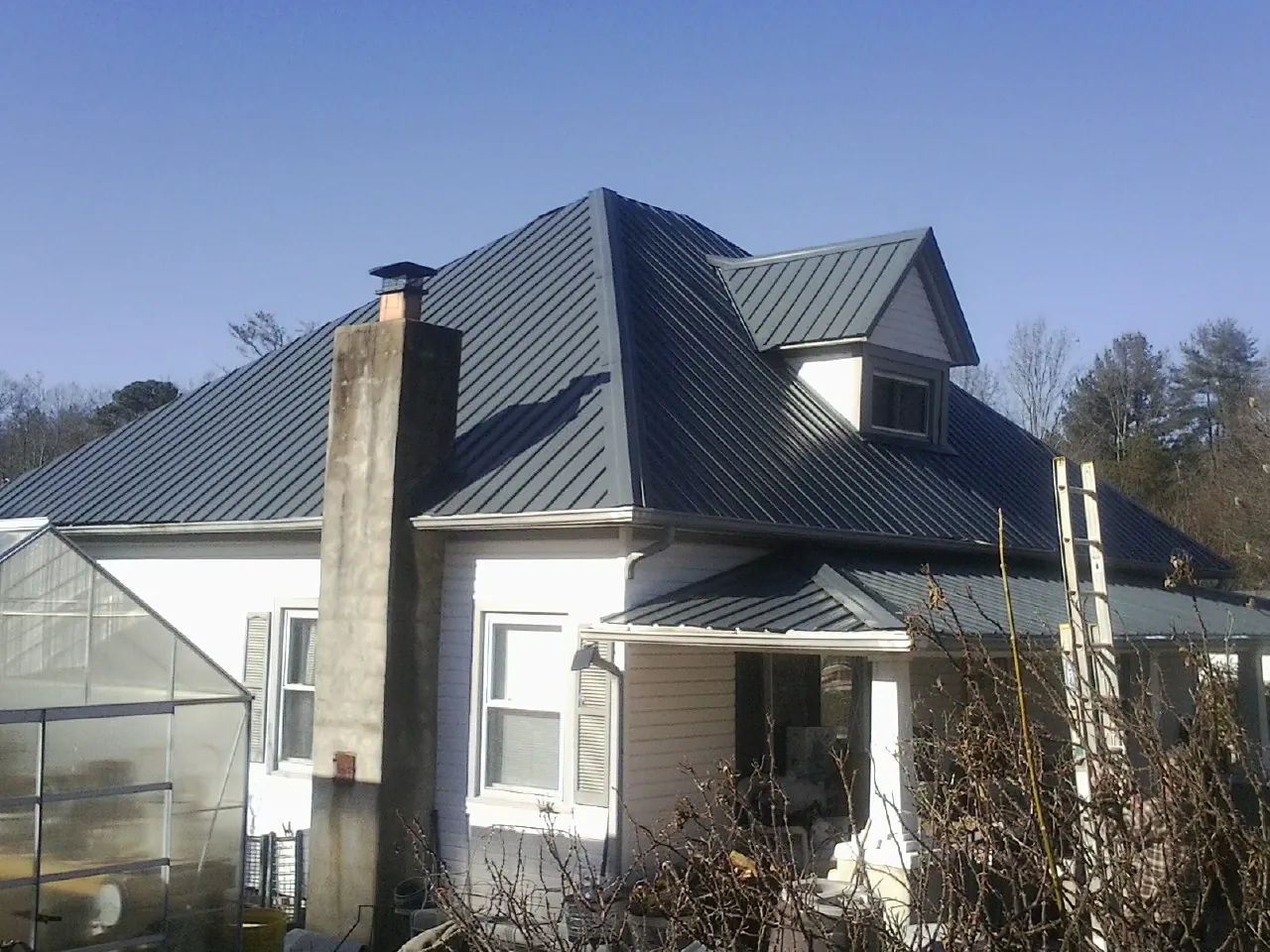 Dark blue standing seam metal roof on a white farmhouse with dormer — Slate & Tile Roof Repair by Roofing Brothers in Warsaw