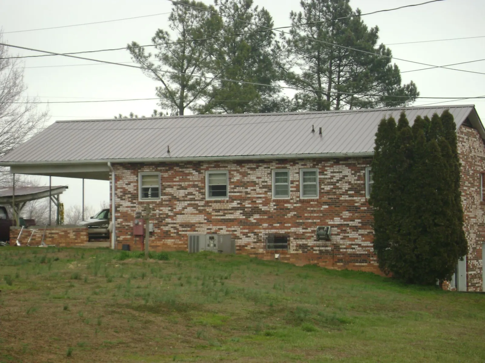 Gray metal roof on a brick split level home with a carport in Warsaw